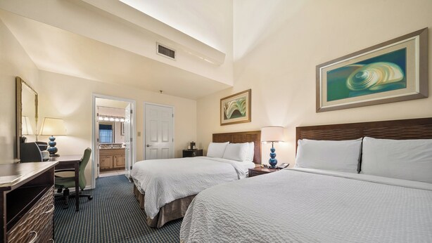 A hotel room with two beds, a desk, a chair, and a bathroom visible through an open door. - Holiday Inn & Suites Clearwater Beach S-Harbourside by IHG (Indian Rocks Beach)
