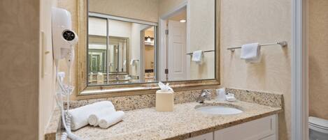 A bathroom with a large mirror, a sink, a towel rack, and a hairdryer.