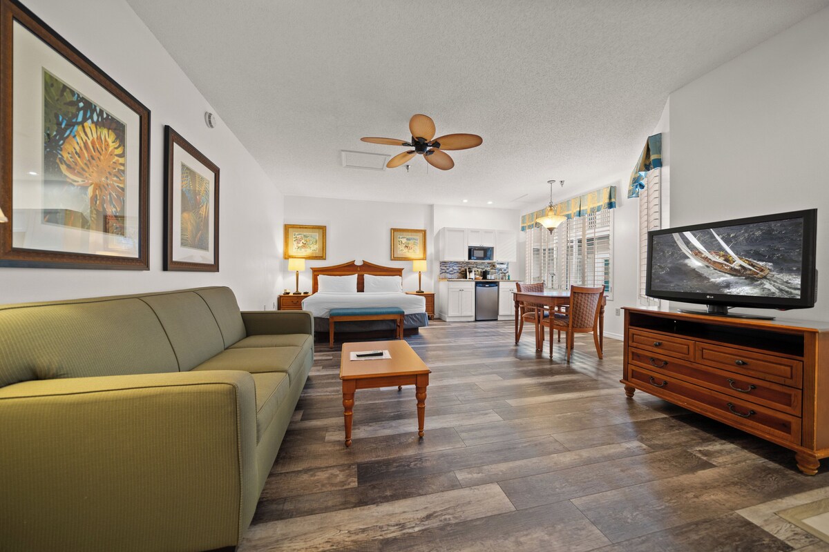 A living room with a sofa, coffee table, TV, and ceiling fan.