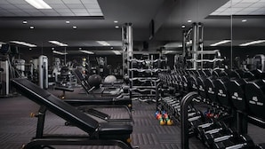 Een fitnessruimte met trainingsapparatuur, gewichtrekken en een spiegelwand.
