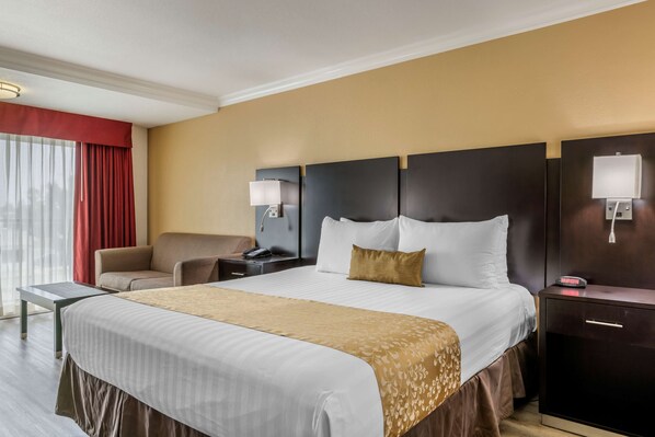 A hotel room with a large bed, a desk, a chair, a nightstand, and a wall-mounted lamp. - Best Western Plus South Bay Hotel (Lawndale)