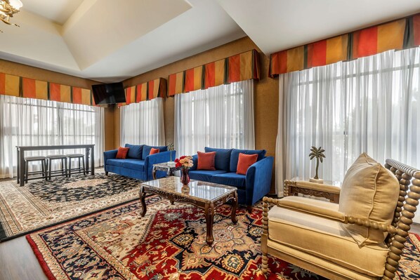 A spacious living room with a blue sofa, beige armchair, and a glass coffee table.