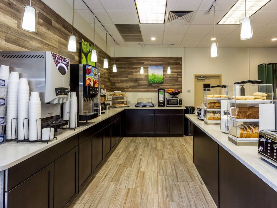 A modern kitchen area with a coffee machine, a microwave, and a bread display.