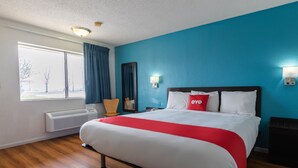 A hotel room with a large bed, a window with curtains, a wall-mounted mirror, and a bedside table. - OYO Hotel DeRidder Hwy 171 North (DeRidder)