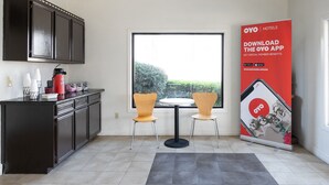 A modern kitchen with dark cabinets, a coffee maker, and two chairs. A large window offers a view of greenery outside. - OYO Hotel DeRidder Hwy 171 North (DeRidder)