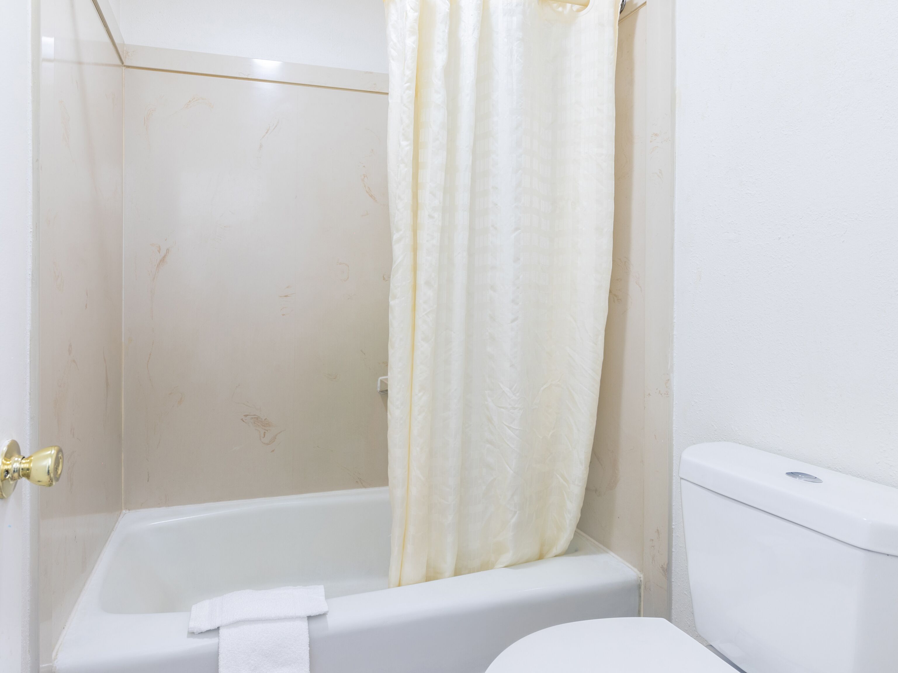 A bathroom with a bathtub, toilet, and a shower curtain.