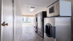 A commercial kitchen with stainless steel appliances, a water dispenser, and a door leading to an outdoor area. - OYO Hotel DeRidder Hwy 171 North (DeRidder)