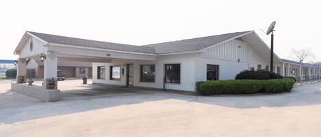 A motel with a covered parking area, a satellite dish, and a well-maintained lawn.