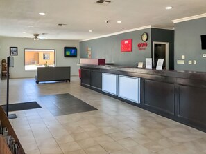 A reception area with a counter, a clock, and a door.