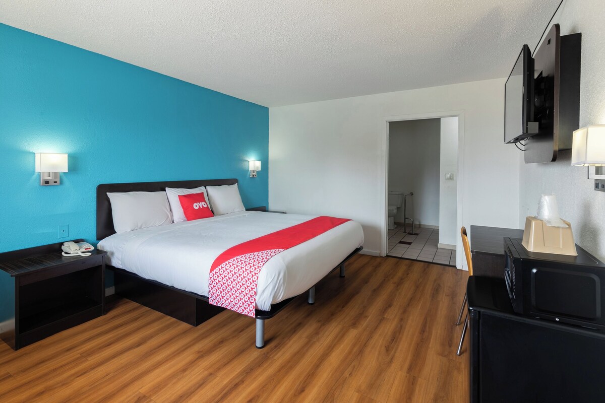 Una habitación de hotel con cama, mesitas de noche, escritorio y televisión.