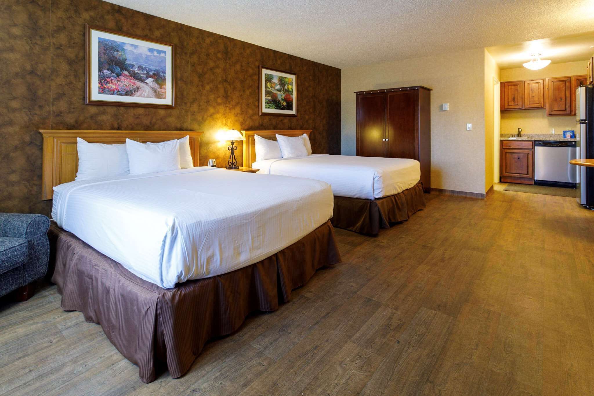 A hotel room with two beds, a kitchenette, and a dining area.