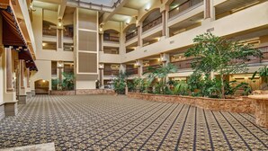 A multi-level atrium with a patterned floor, multiple balconies, and indoor plants. - Radisson Hotel El Paso Airport (El Paso)