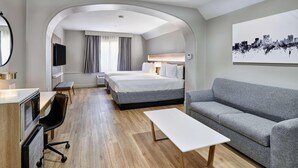 A modern hotel room with a large bed, a sofa, a desk with a computer, and a flat-screen TV. - Radisson Hotel El Paso Airport (El Paso)