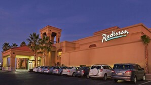 A Radisson hotel with a parking lot and several cars parked in front. - Radisson Hotel El Paso Airport (El Paso)