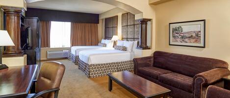 A hotel room with a large bed, a sofa, a desk, and a chair.