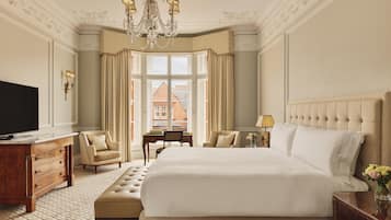 A spacious bedroom with a large bed, a television, a desk, and a chair.