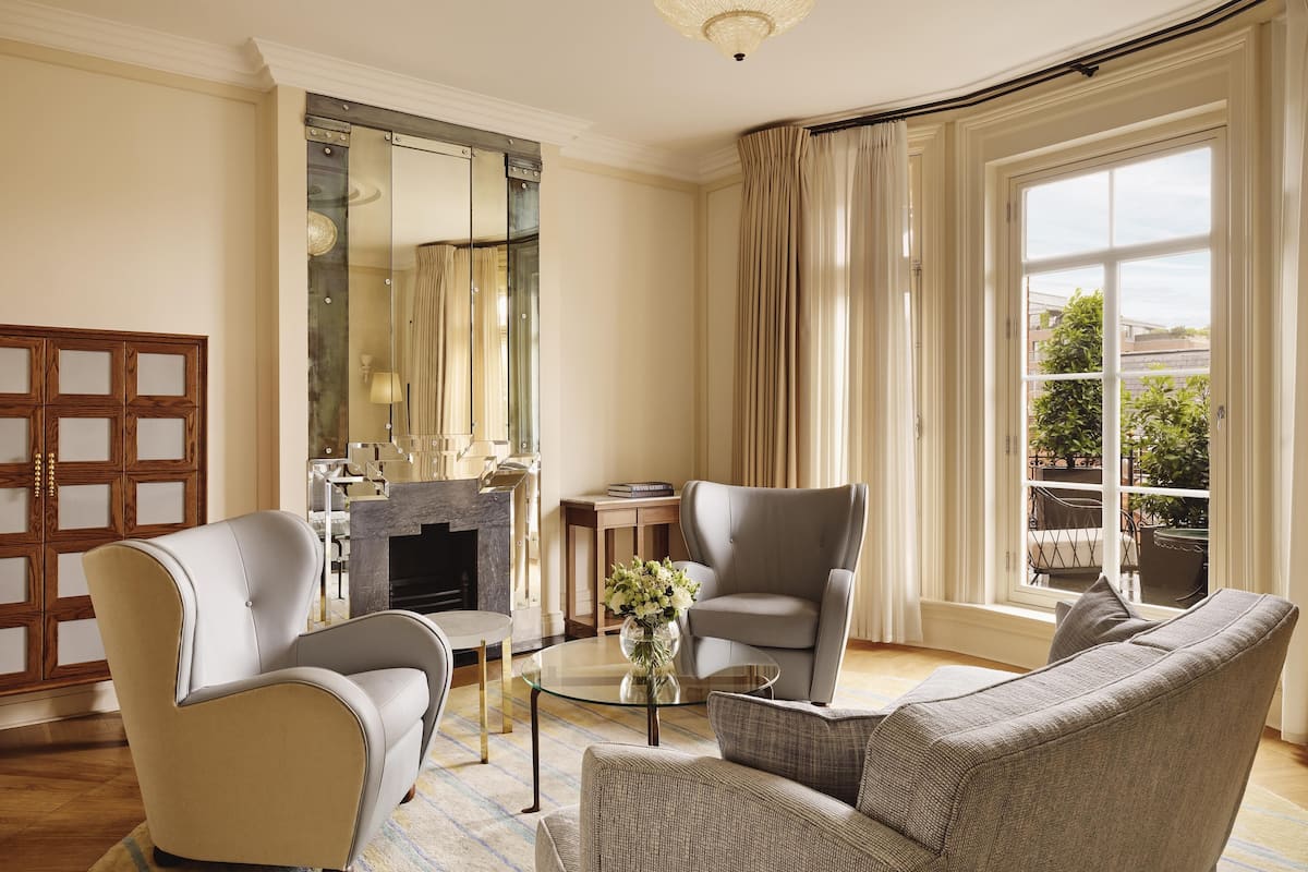 A modern living room with a fireplace, two armchairs, a sofa, and a glass coffee table.