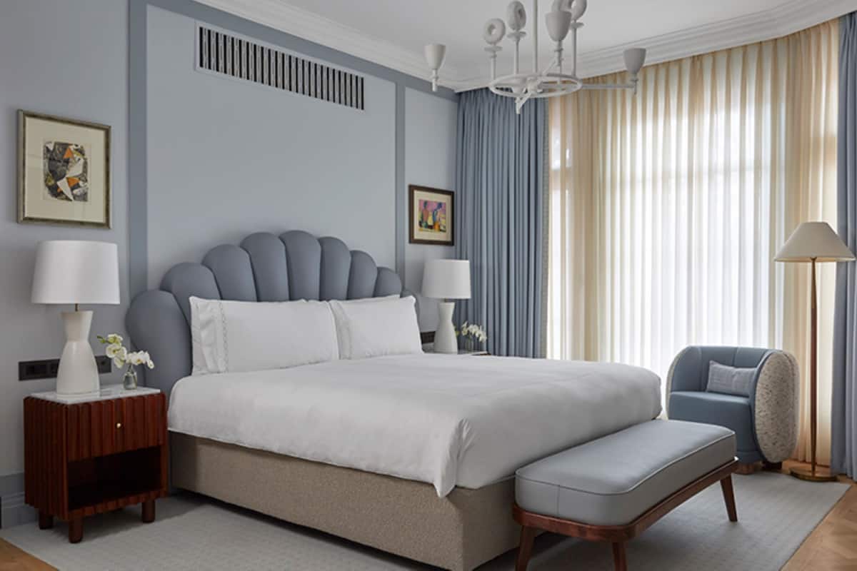 A modern bedroom with a large bed, bedside lamps, a nightstand, a chair, and a floor lamp.