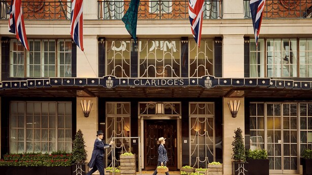 Fachada del hotel Claridge's con grandes ventanales, un cartel luminoso y banderas.