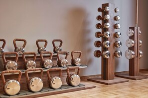 A series of kettlebells and dumbbells arranged on wooden platforms and stands.