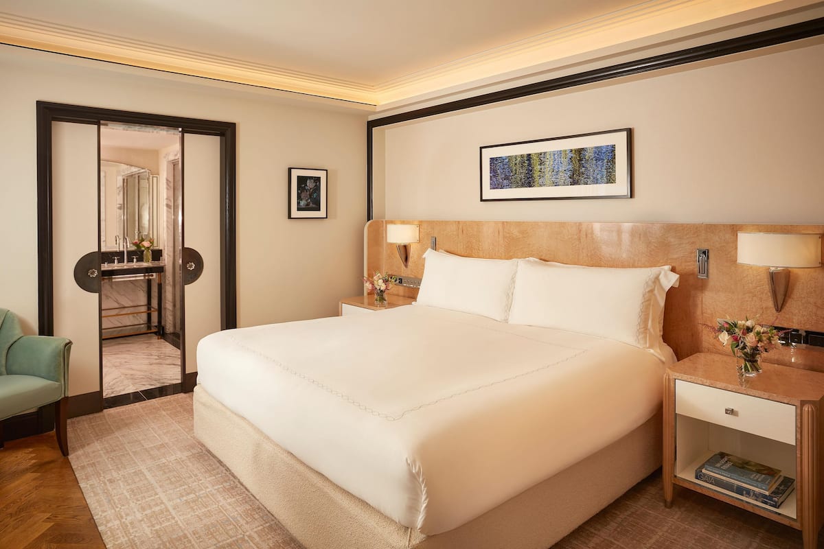 A hotel room with a large bed, bedside tables, a mirror, and a framed picture on the wall.