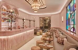 A bar area with a marble counter, shelves of liquor bottles, and a stained glass window.