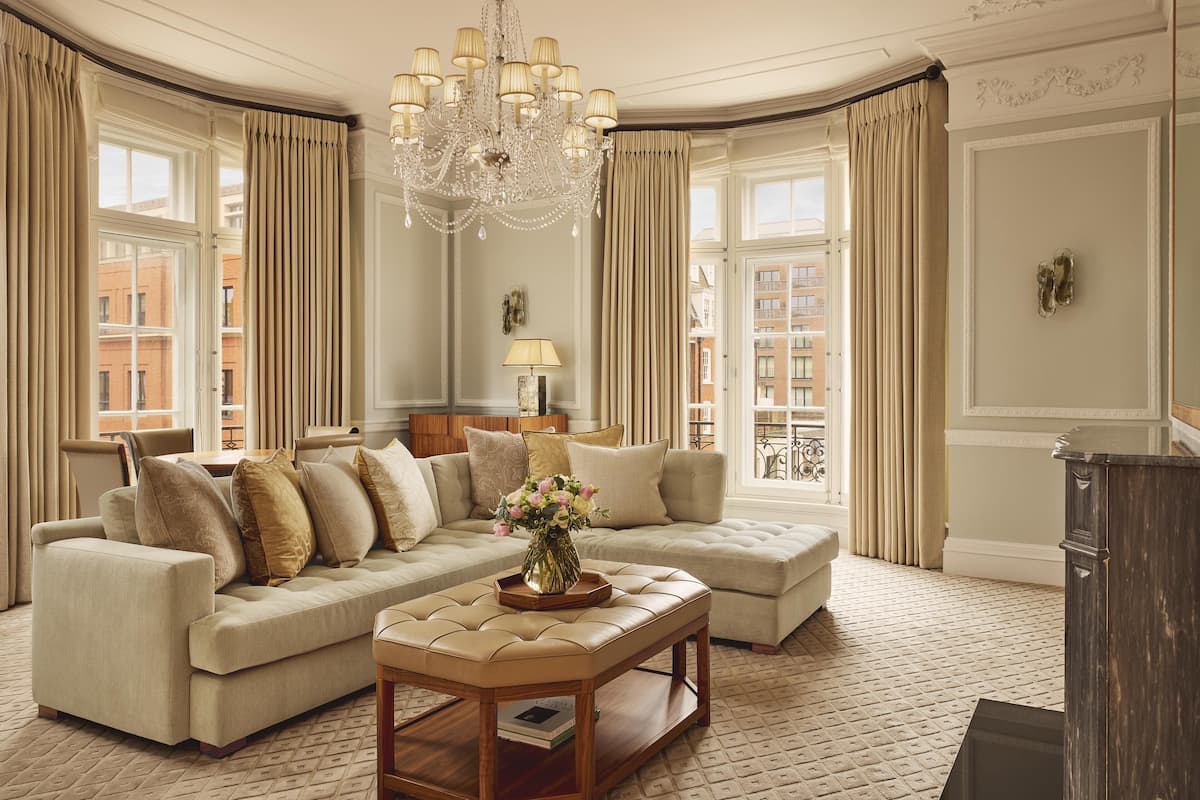 A spacious living room with a large sectional sofa, a wooden coffee table, and a chandelier.