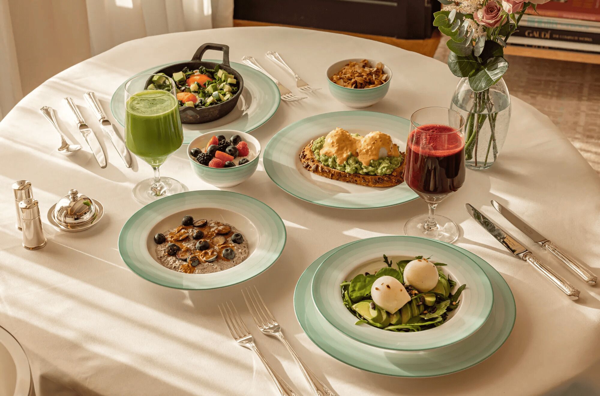 A table set with various dishes, including a salad, a bowl of berries, and a glass of red wine.