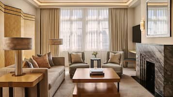 A modern living room with a sofa, two armchairs, a coffee table, a side table, a lamp, a fireplace, and a large window with curtains.