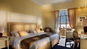 A hotel room with a large bed, two bedside tables, a chair, a desk with a mirror, and a view of the outdoors.