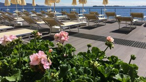 A deck with sun loungers and umbrellas, overlooking a body of water with mountains in the distance. - Grand Hotel Gardone Riviera (Gardone Riviera)