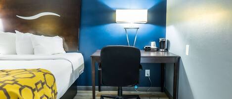 A hotel room with a bed, a desk, a chair, and a nightstand.