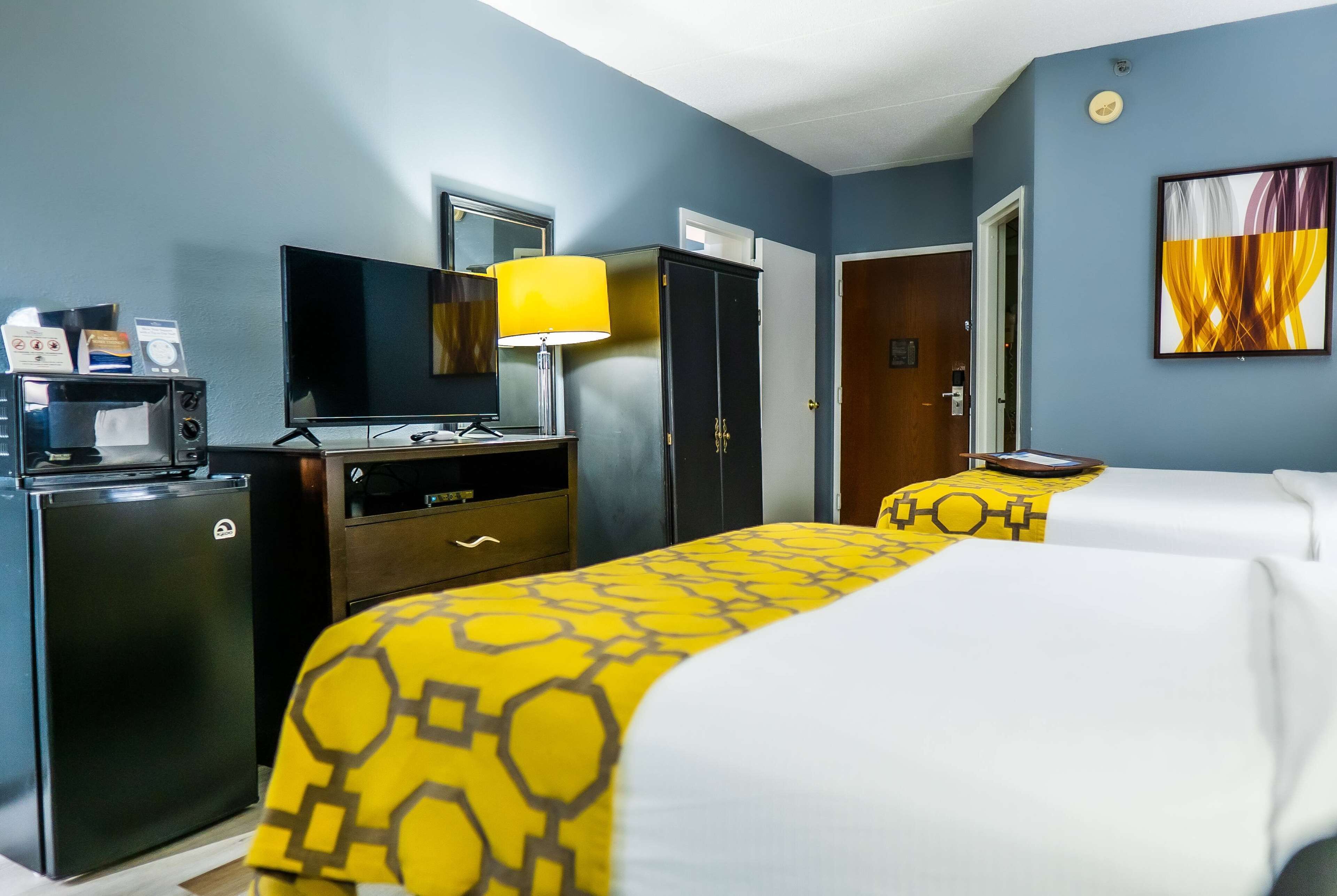 Una habitación de hotel con cama, escritorio, televisión y refrigerador.