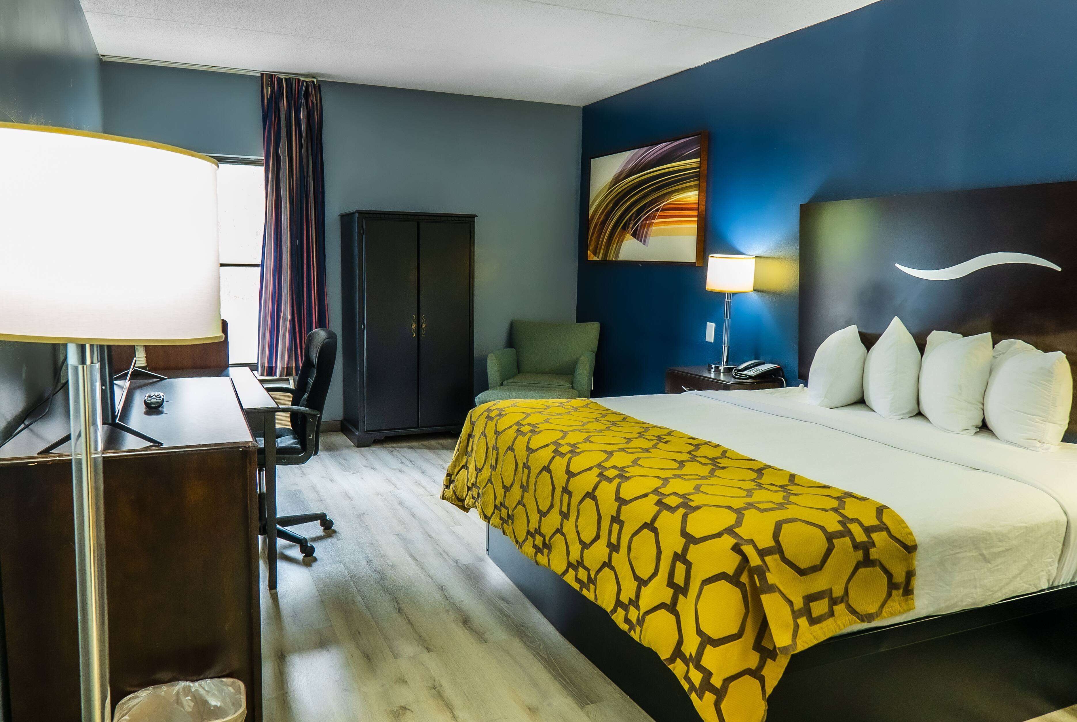 Habitación de hotel con cama, escritorio, silla y armario.