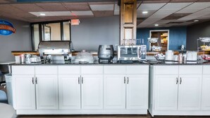 Un espace cuisine doté d’un grand îlot central, d’une machine à café, d’un four à micro-ondes et d’un présentoir pour les aliments.