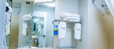 A bathroom with a sink, mirror, towel rack, and shower area.