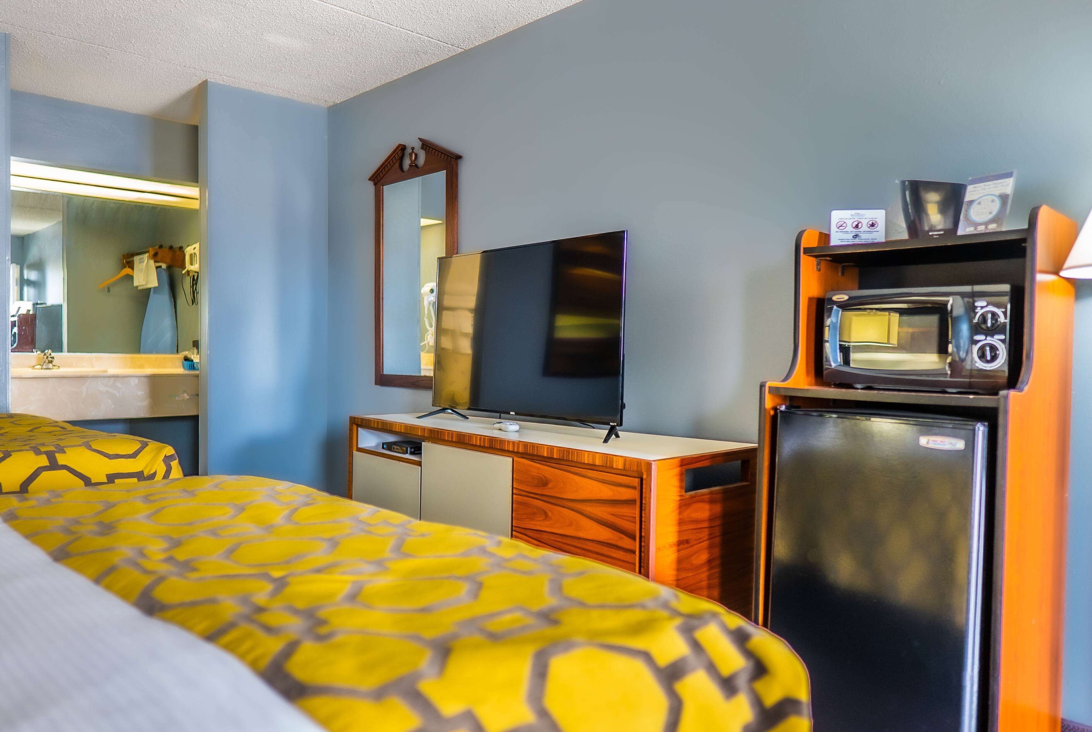 Una habitación de hotel con cama, escritorio, televisor y refrigerador.