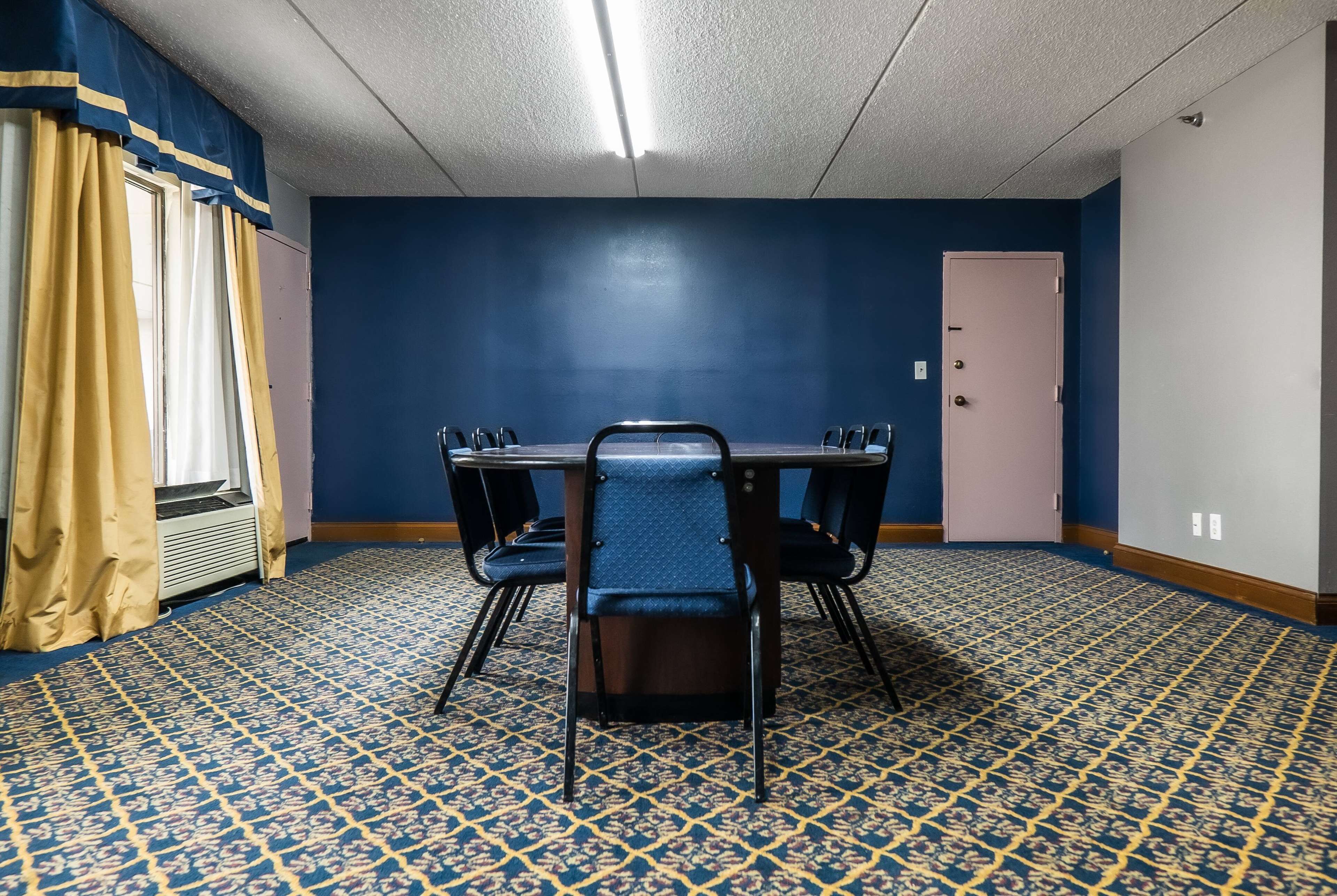 Ein Konferenzraum mit blauem Teppich, einem Tisch und Stühlen sowie einer Tür.