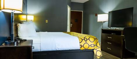 Habitación de hotel con una cama, lámparas de noche, un escritorio con teléfono, cómoda, televisor y una puerta que da a otra habitación.