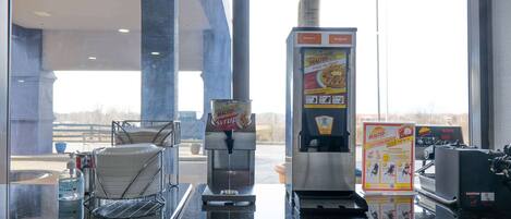 A coffee machine, a syrup dispenser, and a caution sign on a counter.