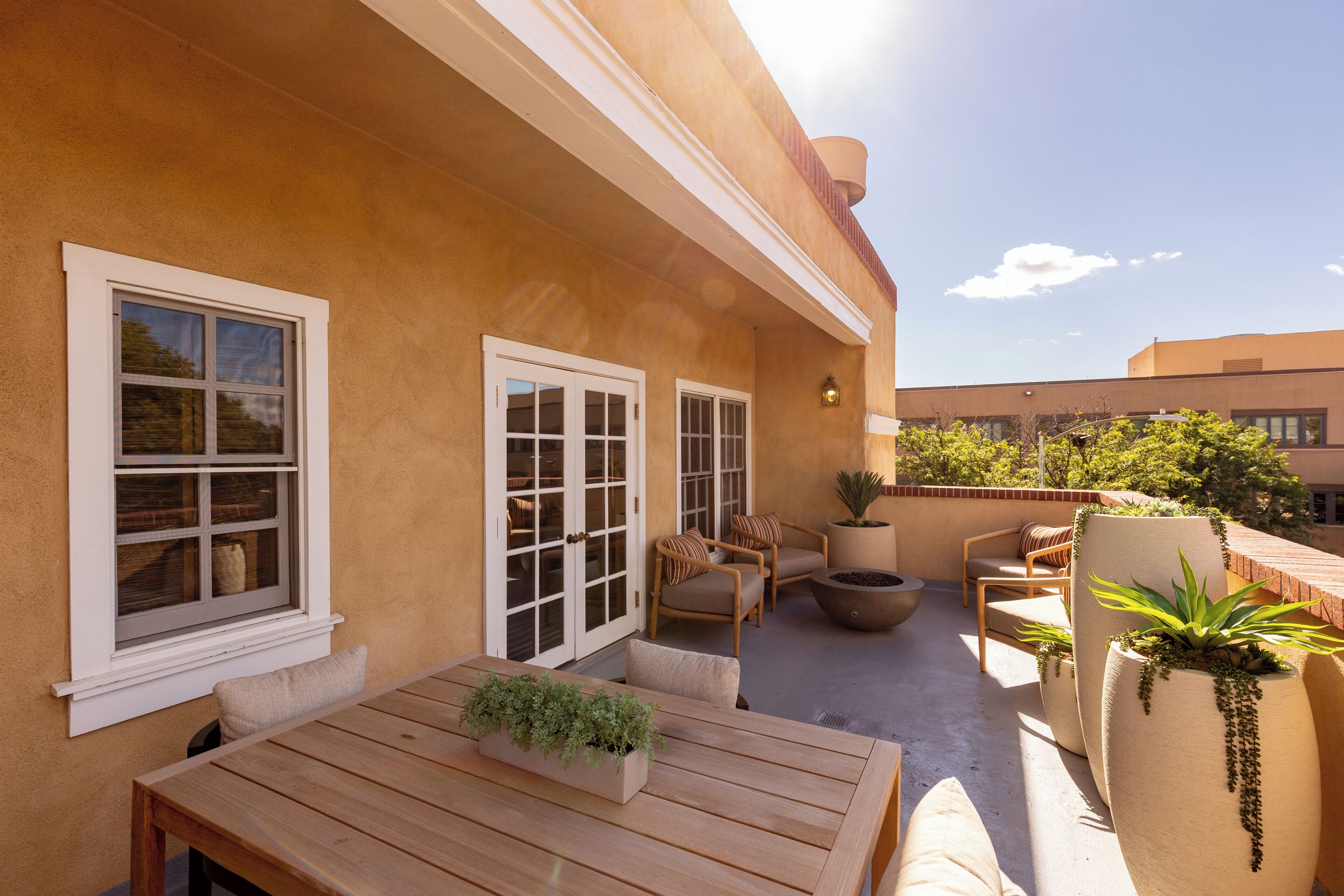 A patio with a wooden table, chairs, and potted plants.