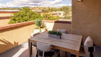 A balcony with a table and chairs, a potted plant, and a view of the landscape.