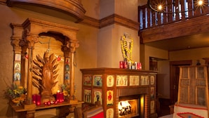 A warmly lit room with a wooden altar, a fireplace, and a wooden bench.
