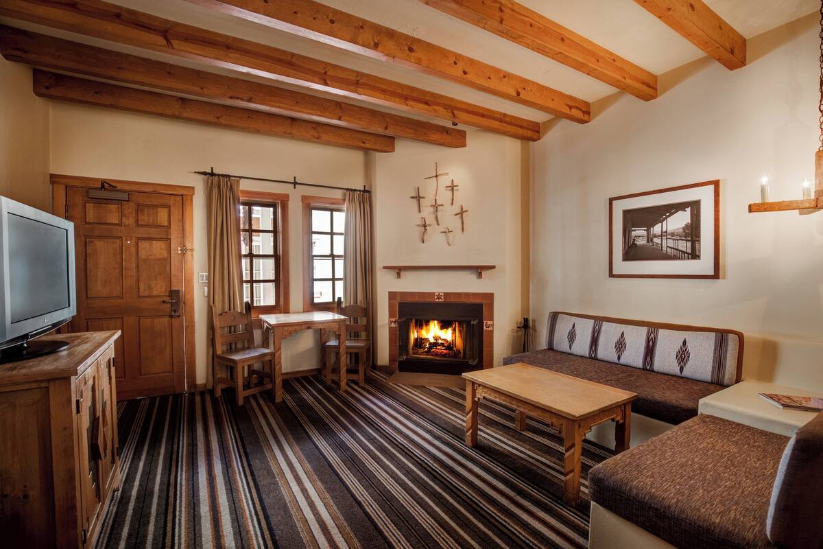 A cozy living room with a fireplace, wooden furniture, and a television.