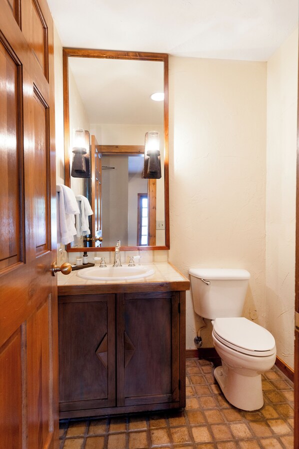 A bathroom with a wooden vanity, a mirror, a toilet, and a tiled floor. - Hotel Chimayo de Santa Fe (Santa Fe)