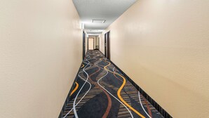 Ein Hotelgang mit Teppichmuster, beige Wänden und einer Deckenleuchte.