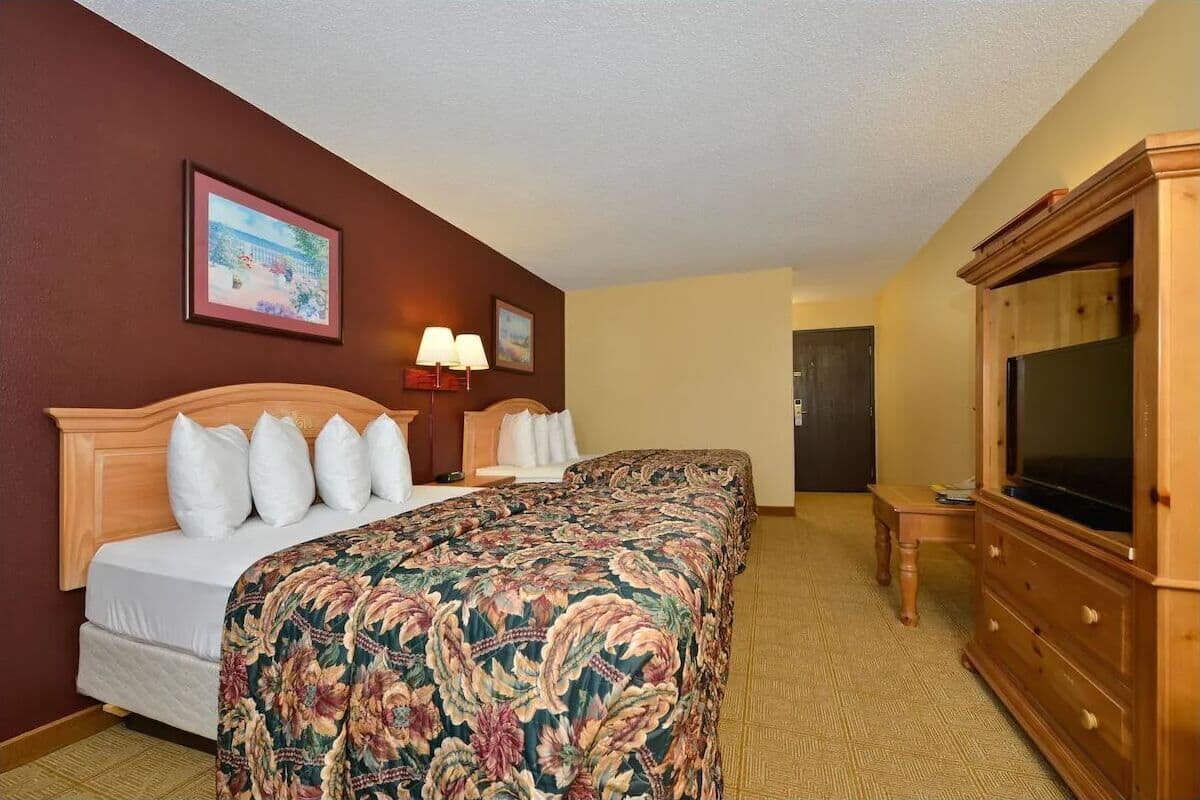 A hotel room with a bed, a television, a dresser, and a framed picture on the wall.