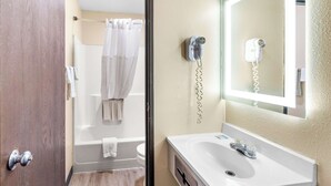 A bathroom with a white sink, a mirror, a hairdryer, and a shower curtain.