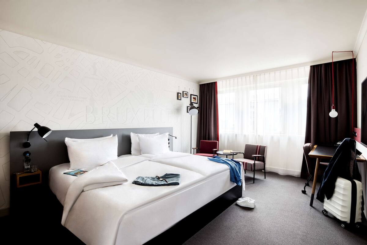 Une chambre d’hôtel avec un grand lit, un bureau, une chaise, une lampe et une armoire.
