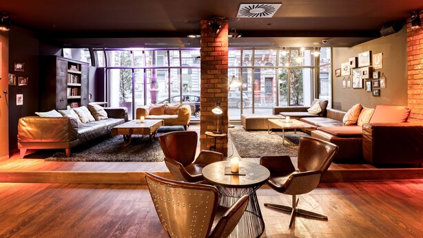 Un área de lounge moderna con sofás de cuero, una mesa redonda y un pilar de ladrillo.